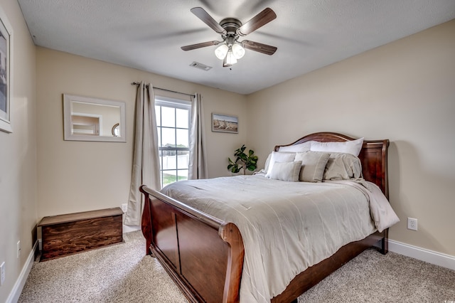 bedroom featuring light colored carpet, a textured ceiling, and ceiling fan