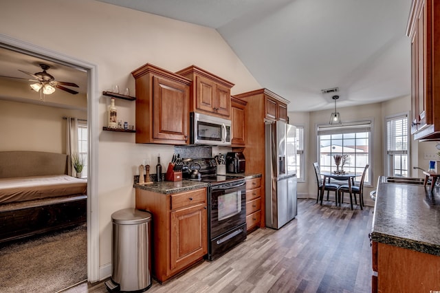 kitchen with lofted ceiling, stainless steel appliances, tasteful backsplash, decorative light fixtures, and light wood-type flooring