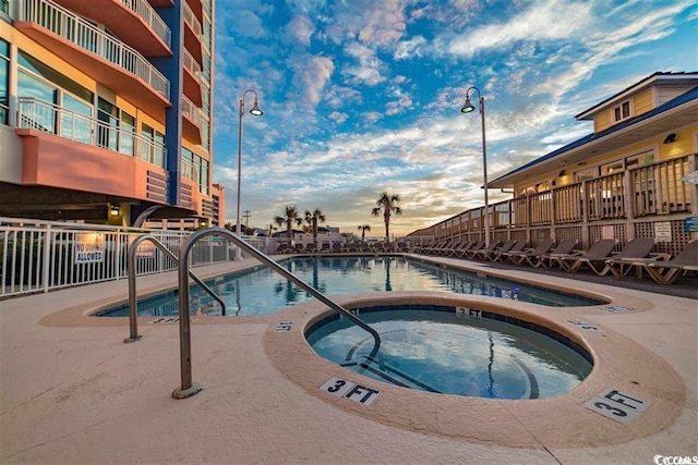 pool at dusk with a community hot tub