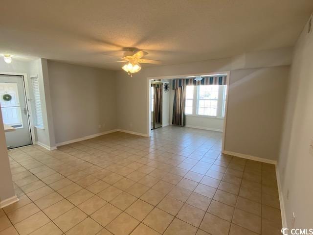 tiled empty room with ceiling fan and a textured ceiling