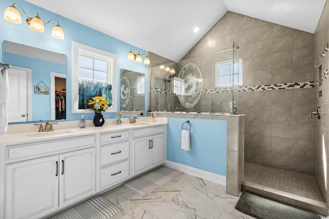 bathroom featuring vaulted ceiling, tiled shower, and vanity