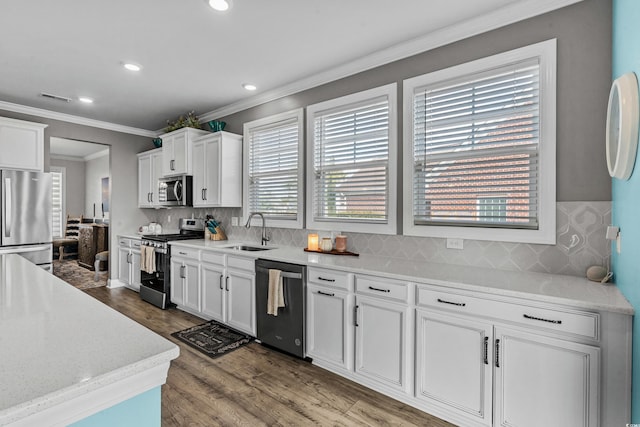 kitchen featuring white cabinetry, sink, backsplash, hardwood / wood-style flooring, and stainless steel appliances