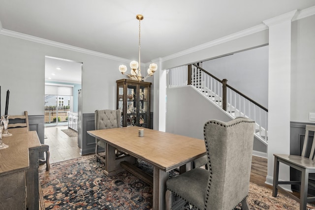 dining area with an inviting chandelier, wood-type flooring, and ornamental molding