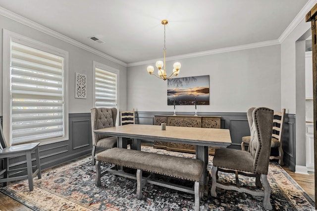 dining area with hardwood / wood-style floors, ornamental molding, and a chandelier