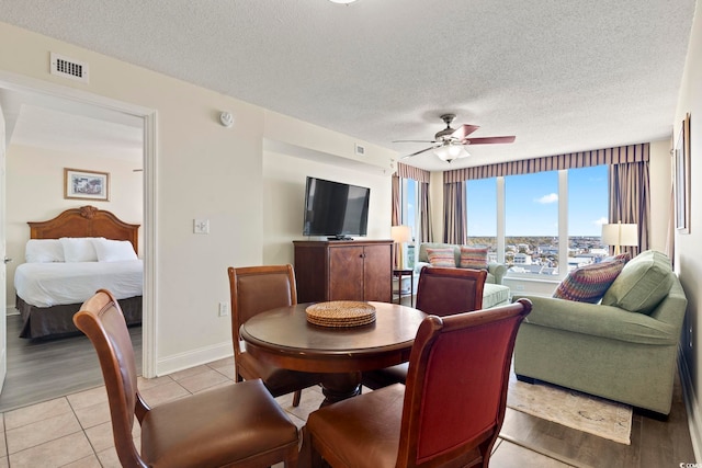 dining space featuring a textured ceiling, ceiling fan, and light tile patterned flooring