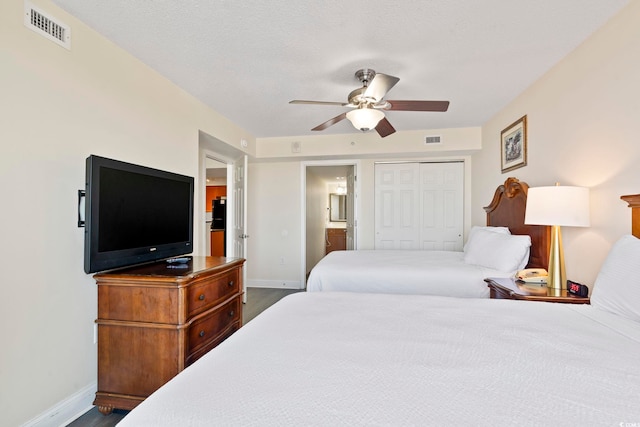 bedroom with connected bathroom, a textured ceiling, dark hardwood / wood-style floors, a closet, and ceiling fan