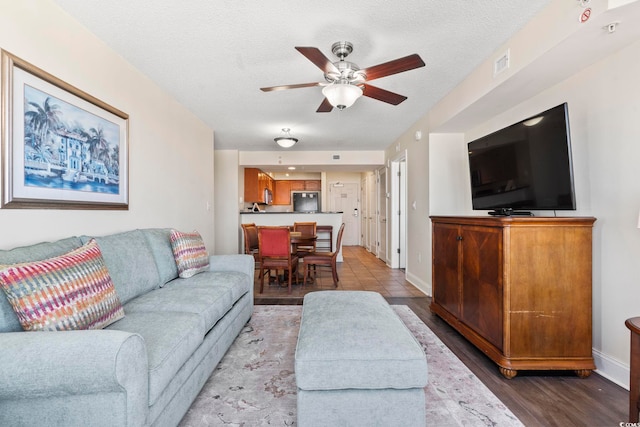 living room featuring a textured ceiling, ceiling fan, and hardwood / wood-style flooring