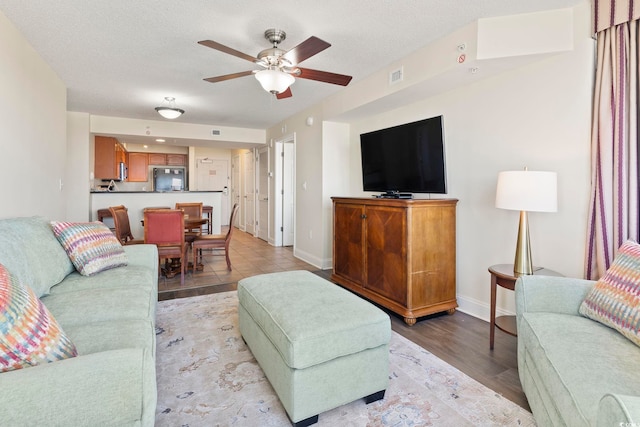 living room with a textured ceiling, light hardwood / wood-style floors, and ceiling fan