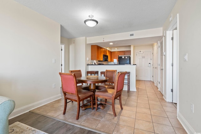 dining area featuring a textured ceiling and light tile patterned flooring