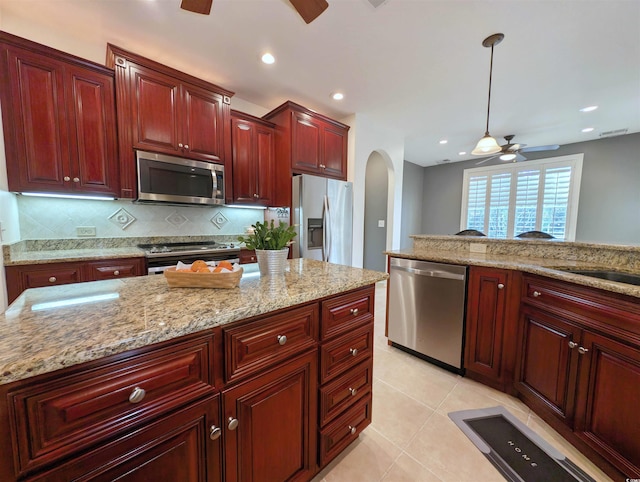 kitchen with pendant lighting, light tile patterned floors, ceiling fan, stainless steel appliances, and light stone countertops