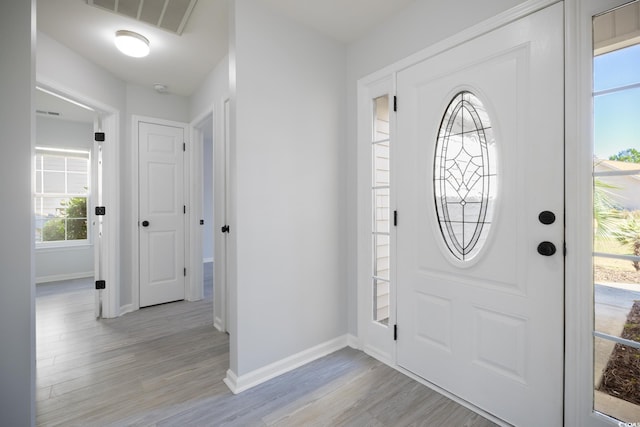 foyer entrance with light wood finished floors, baseboards, and visible vents