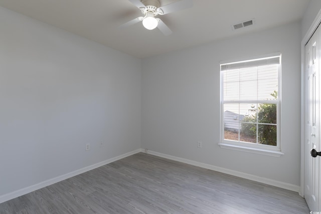 spare room with visible vents, ceiling fan, baseboards, and wood finished floors