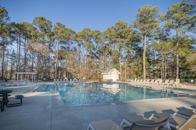 community pool with a patio and fence