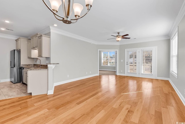 unfurnished living room with crown molding, ceiling fan with notable chandelier, and light wood-type flooring