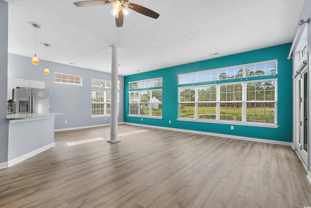 unfurnished living room with light hardwood / wood-style flooring, ceiling fan, and ornate columns