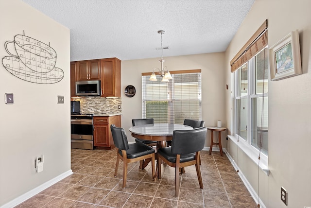 dining area featuring dark tile patterned floors, a textured ceiling, and a chandelier