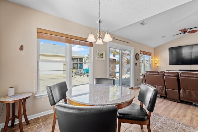 dining area featuring lofted ceiling, ceiling fan with notable chandelier, and a textured ceiling