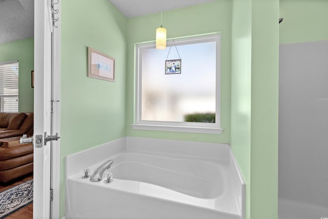 bathroom featuring a tub to relax in and a textured ceiling