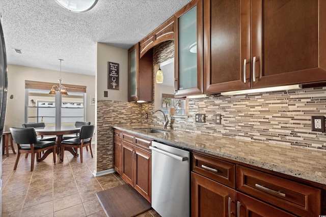 kitchen featuring sink, hanging light fixtures, backsplash, light stone countertops, and stainless steel dishwasher