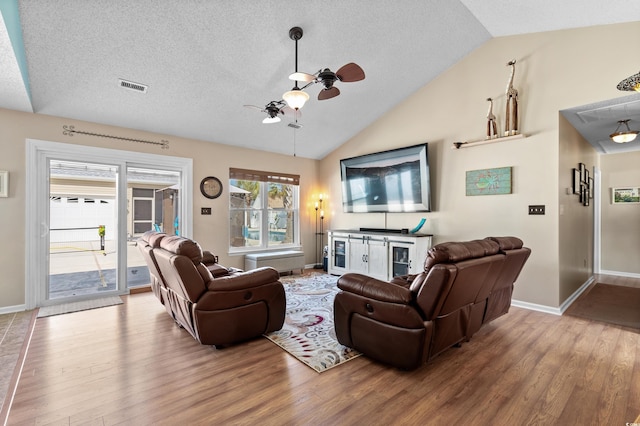 living room with vaulted ceiling, hardwood / wood-style floors, ceiling fan, and a textured ceiling