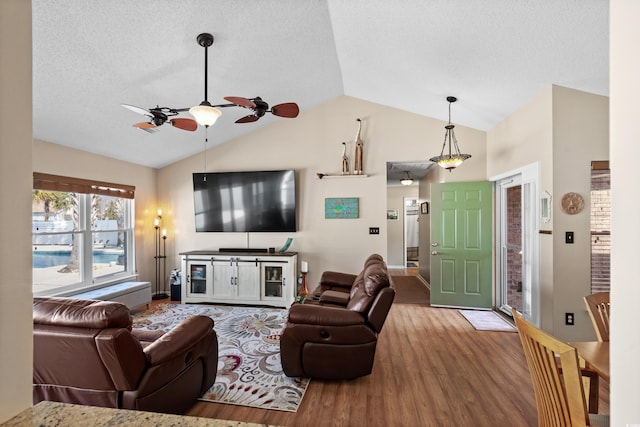 living room featuring ceiling fan, lofted ceiling, hardwood / wood-style floors, and a textured ceiling