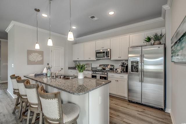 kitchen featuring light wood finished floors, visible vents, ornamental molding, stainless steel appliances, and a sink