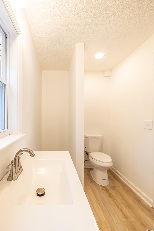 bathroom with wood-type flooring, toilet, a textured ceiling, and vanity