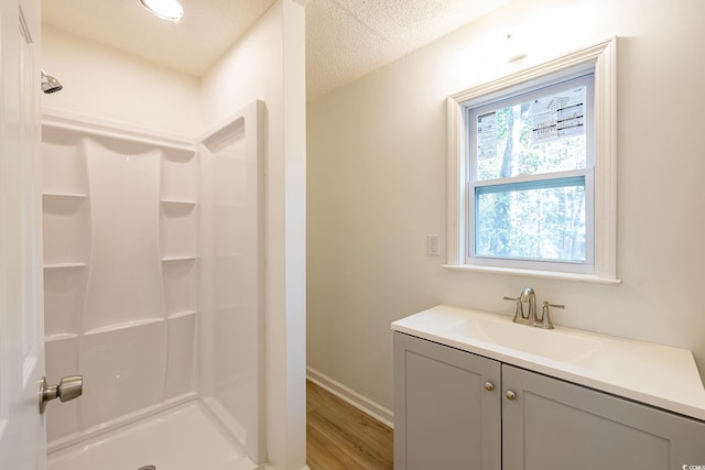 bathroom with vanity, hardwood / wood-style floors, a textured ceiling, and walk in shower