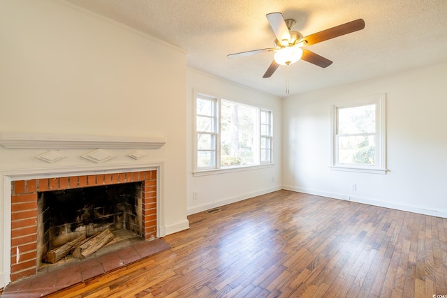 living room with hardwood / wood-style flooring, ceiling fan, a brick fireplace, and a textured ceiling