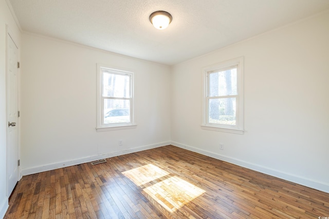 unfurnished room featuring crown molding, wood-type flooring, and a textured ceiling