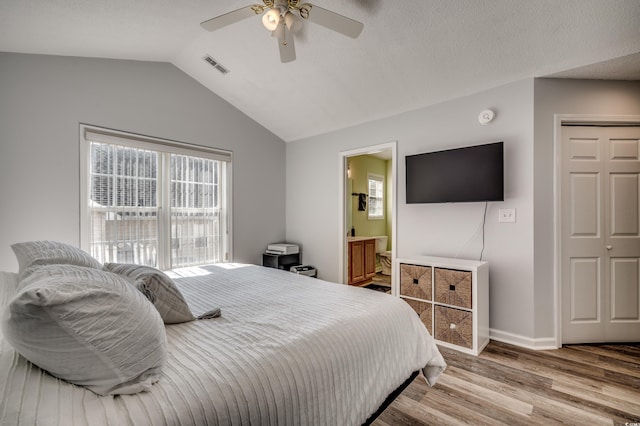 bedroom featuring multiple windows, lofted ceiling, light wood-type flooring, and ensuite bath