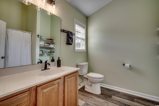 bathroom featuring lofted ceiling, hardwood / wood-style flooring, vanity, a textured ceiling, and toilet