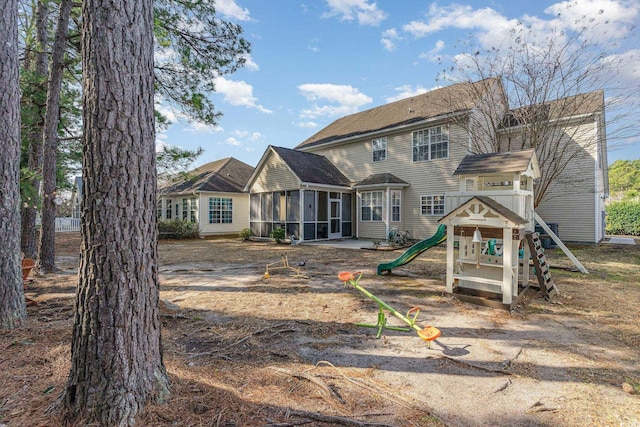 rear view of house featuring a playground and a sunroom