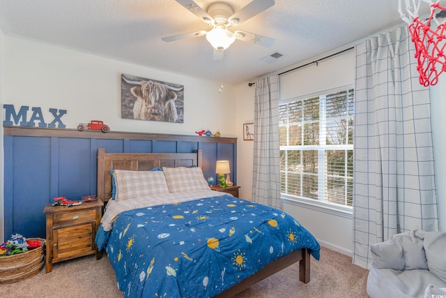 carpeted bedroom featuring ceiling fan and a textured ceiling