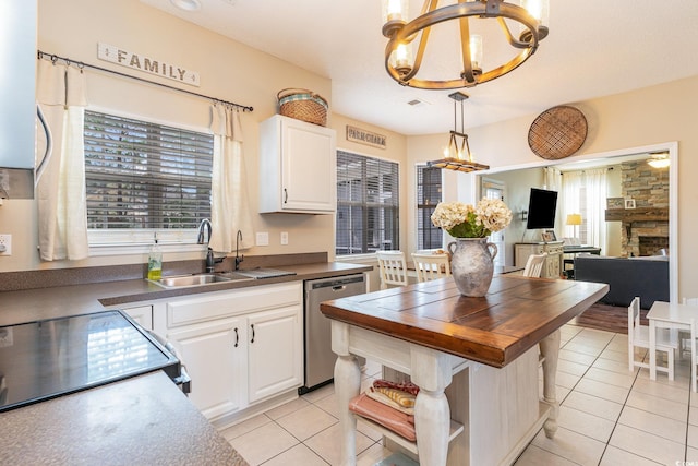 kitchen featuring wood counters, a chandelier, stainless steel dishwasher, pendant lighting, and white cabinets