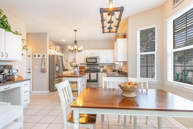 kitchen featuring sink, appliances with stainless steel finishes, white cabinetry, hanging light fixtures, and a chandelier