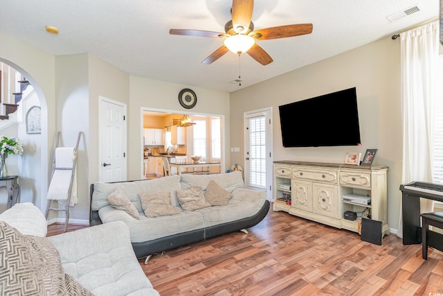 living room featuring ceiling fan with notable chandelier, hardwood / wood-style floors, and a textured ceiling