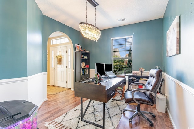 office area featuring plenty of natural light, light hardwood / wood-style floors, a textured ceiling, and a notable chandelier