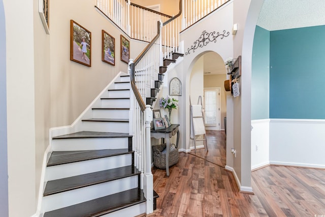 stairway featuring hardwood / wood-style flooring and a towering ceiling