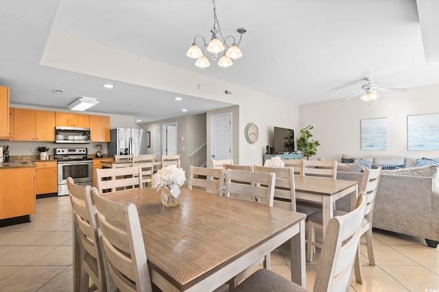 tiled dining area featuring ceiling fan with notable chandelier and sink