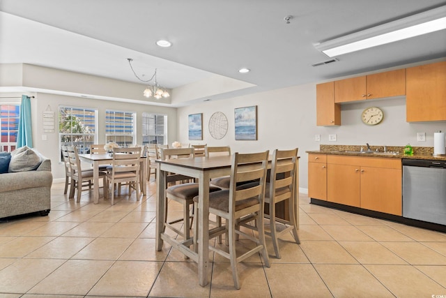 tiled dining area with an inviting chandelier, sink, and a raised ceiling