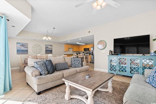 tiled living room with a tray ceiling and ceiling fan with notable chandelier