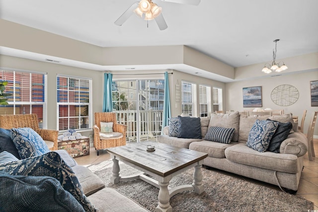 living room with ceiling fan with notable chandelier and light tile patterned floors