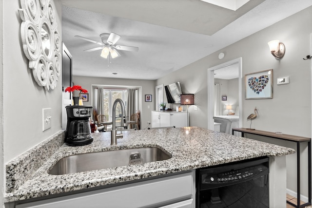 kitchen featuring ceiling fan, black dishwasher, sink, and light stone countertops