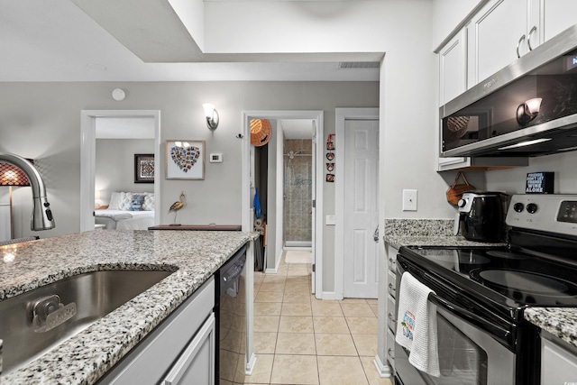 kitchen with sink, light tile patterned floors, appliances with stainless steel finishes, light stone countertops, and white cabinets