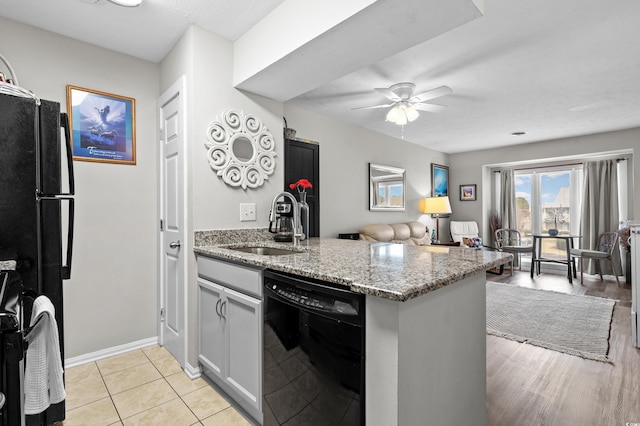 kitchen with stone counters, black appliances, sink, ceiling fan, and kitchen peninsula