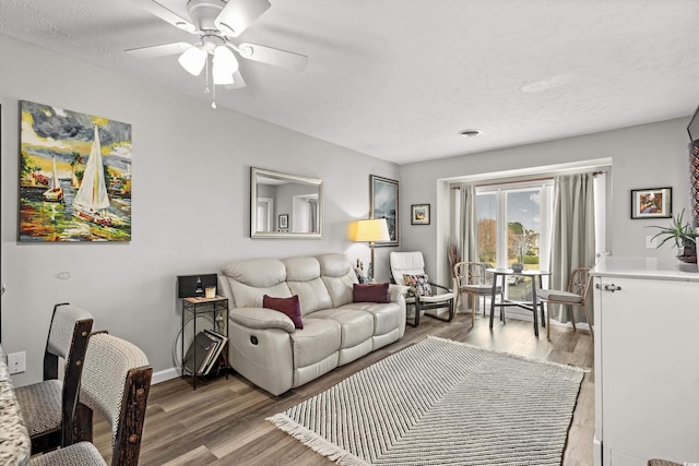 living room featuring ceiling fan, wood-type flooring, and a textured ceiling