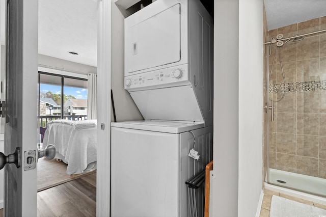 clothes washing area with stacked washer and dryer and light hardwood / wood-style floors