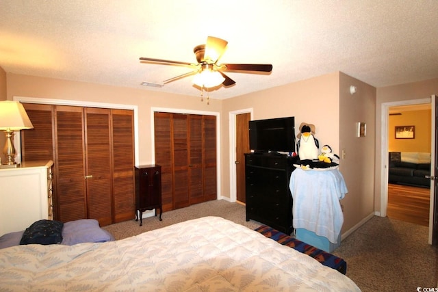 bedroom with ceiling fan, carpet, two closets, and a textured ceiling