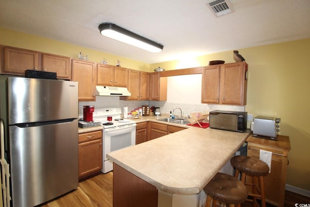 kitchen featuring sink, stainless steel fridge, a breakfast bar, white range with electric cooktop, and backsplash